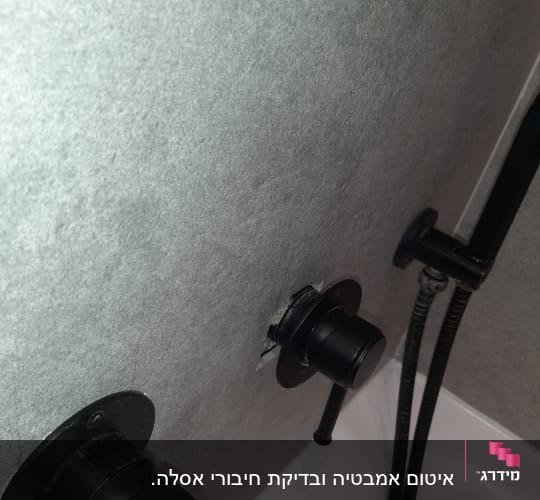 ברזים שחורים על קיר אפור בחדר אמבטיה
